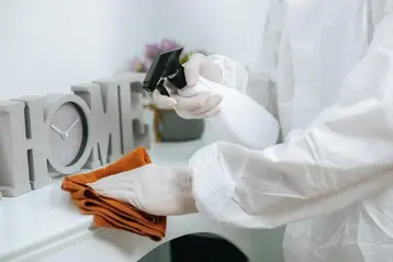 Disinfection specialist in a PPE suit applying housekeeping detergent