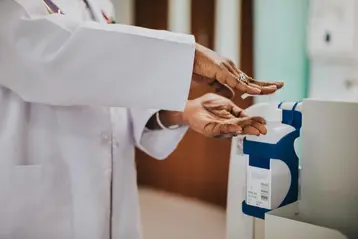 Physician sanitizing her hands with a hand sanitizer