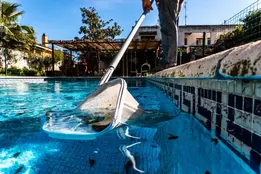 Pool maintenance technician skimming a swimming pool
